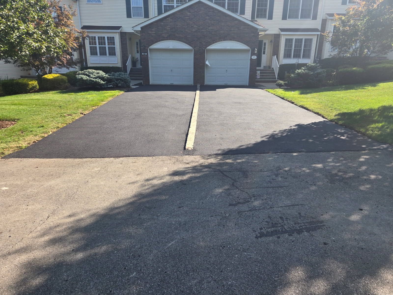 Suburban house with a double garage and two fresh black asphalt driveways leading to the street