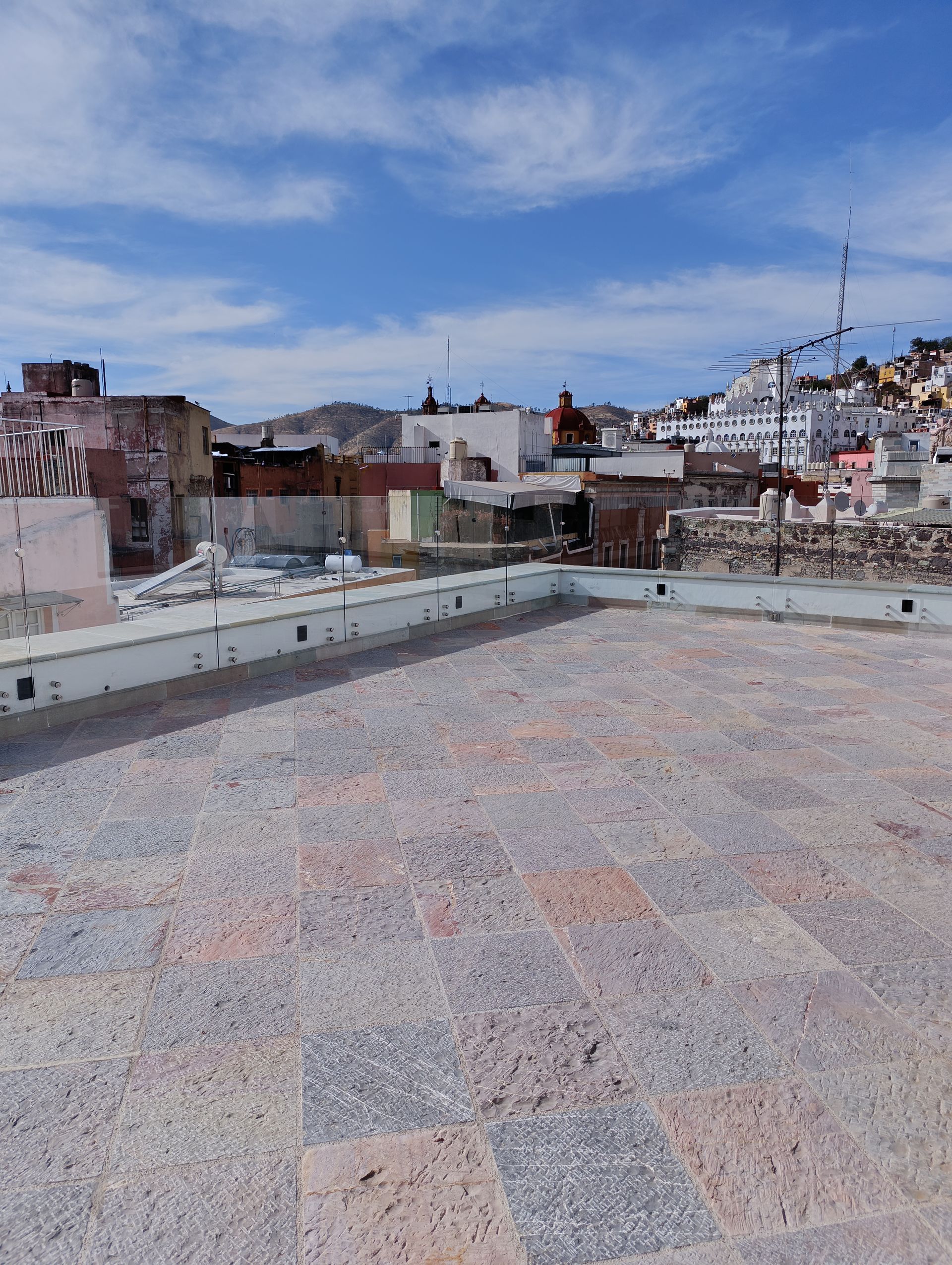 Vista desde la azotea de un paisaje urbano con edificios blancos bajo un cielo azul.