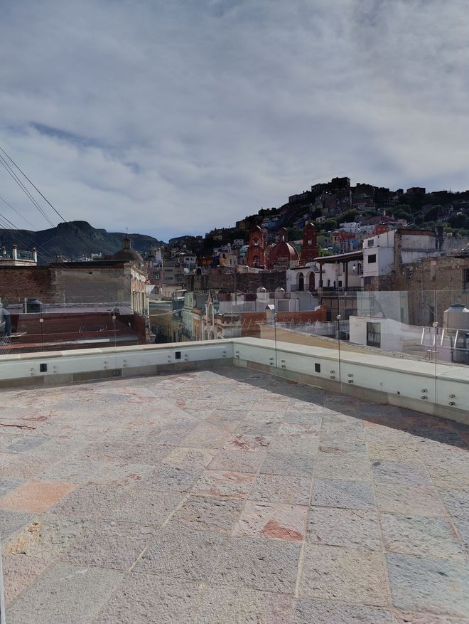 Vista aérea de un pueblo enclavado en las colinas bajo un cielo nublado. Los edificios se agrupan en las laderas.