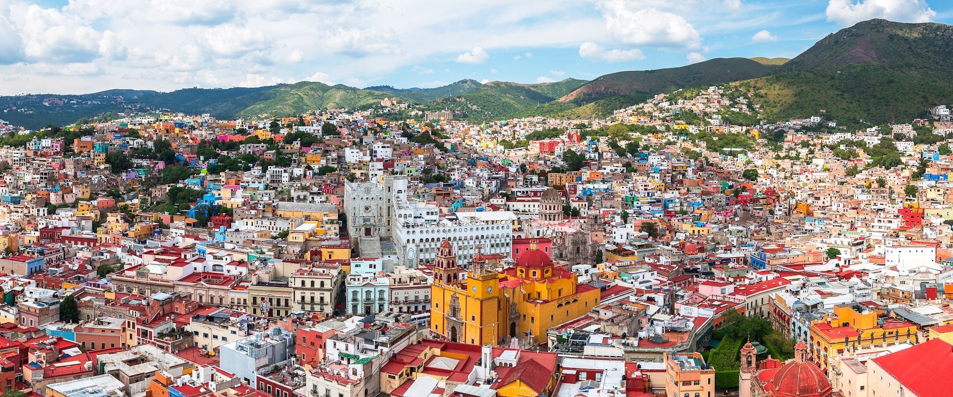Panorama de una ciudad colorida construida en una ladera bajo un cielo nublado.