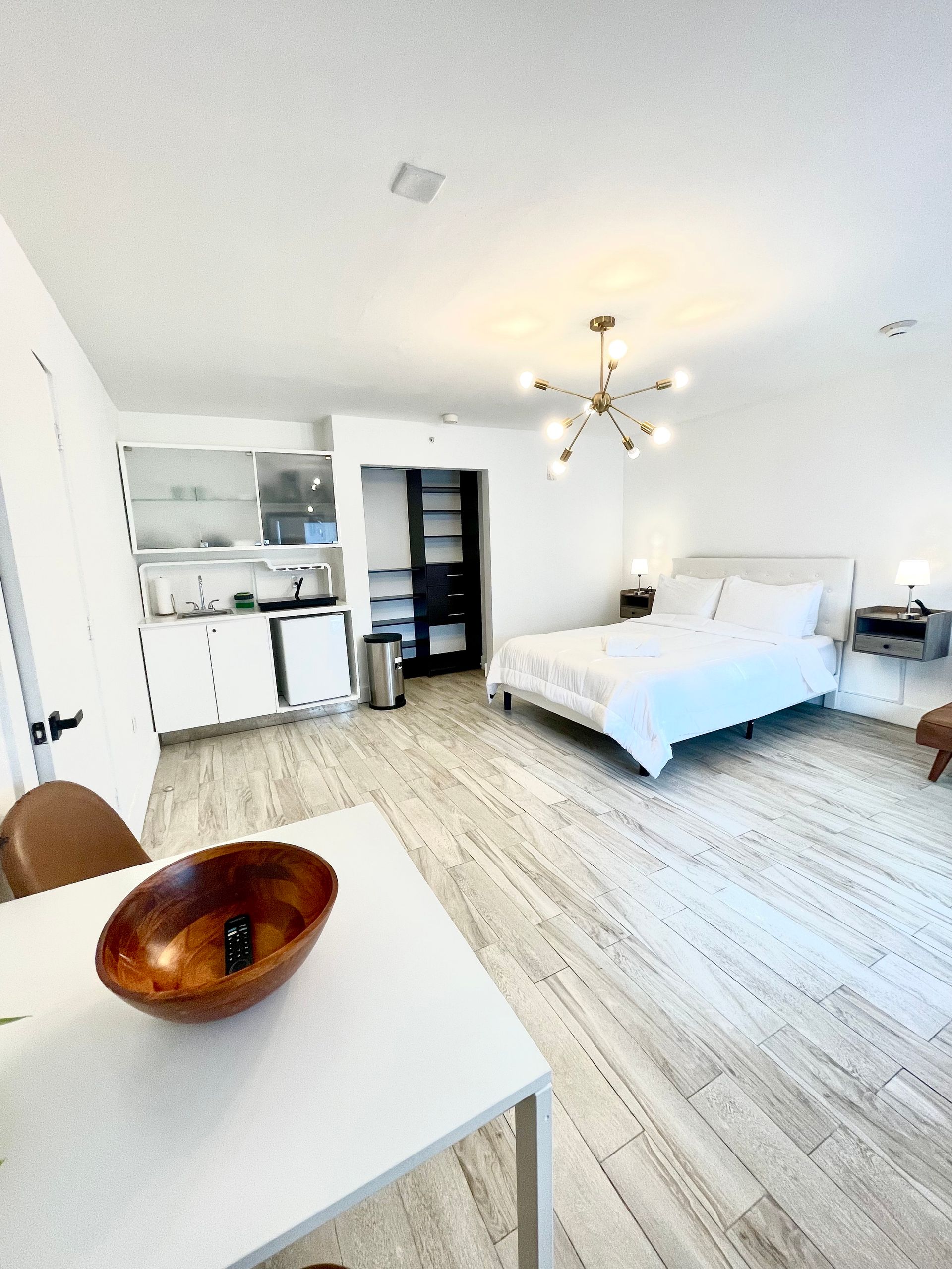 Bright, modern studio apartment with kitchen, bed, dining table, and light wood floors.