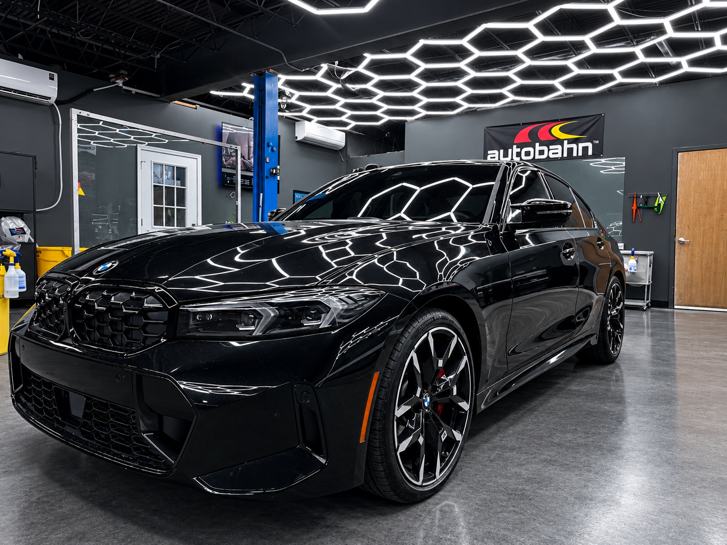 Black SUV in a modern auto shop with hexagonal ceiling lights and a AutoBahn sign