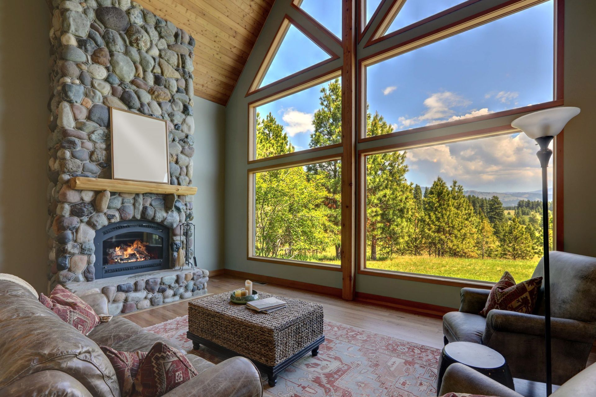 What Type of Energy Savings Can I Expect From Window Films for My Home or Office? Cozy living room with stone fireplace, large windows, and a view of trees and sky.