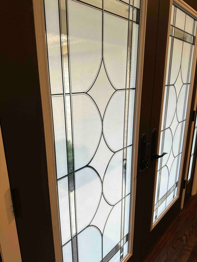 Double doors with decorative frosted glass panels outlined in black. Wooden frames.