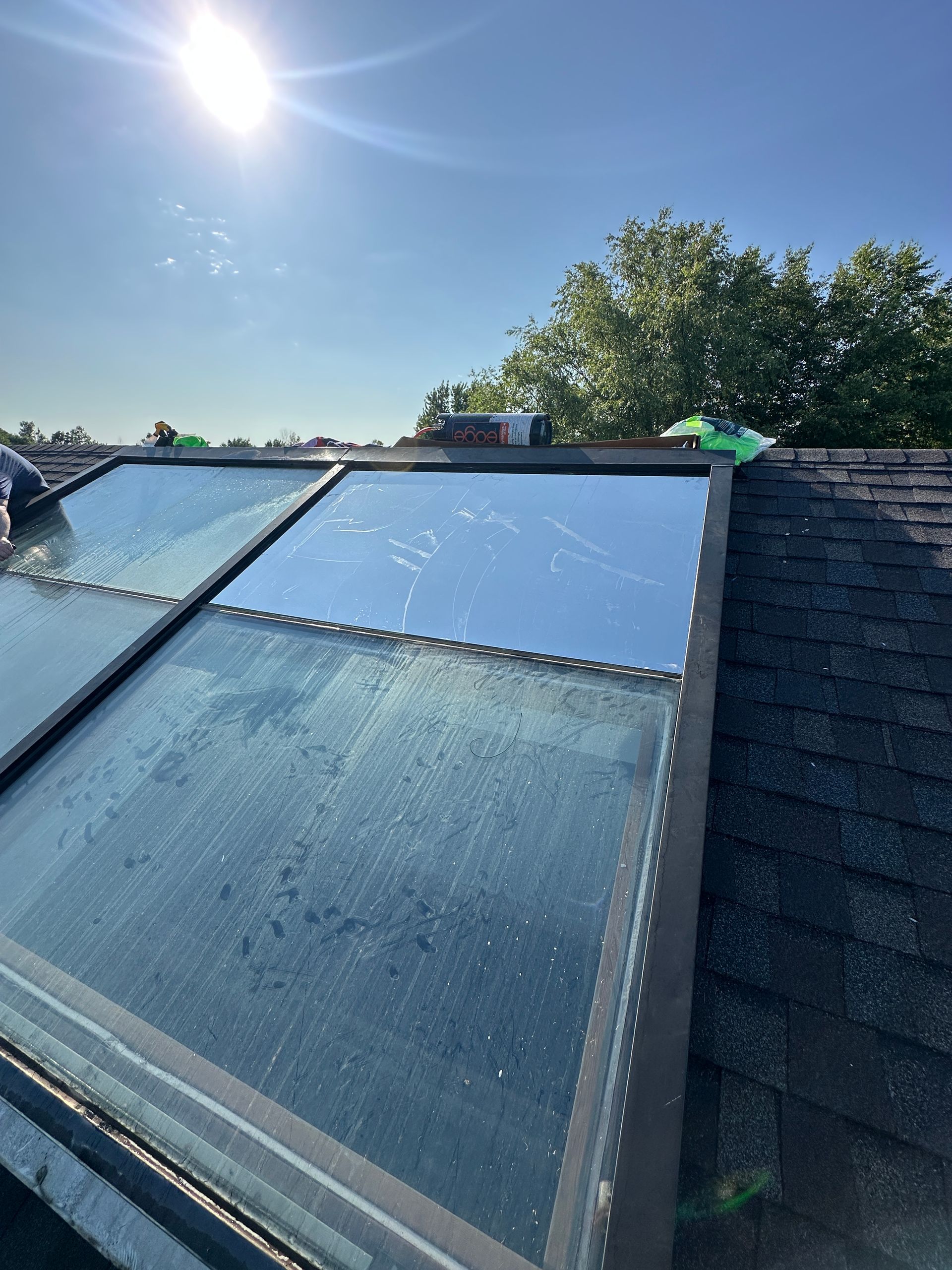 Skylights on a dark shingled roof under a sunny blue sky.