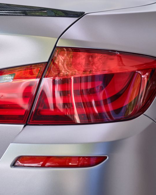 Close-up of a silver car's red tail light.