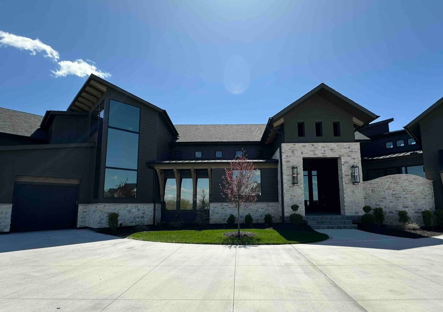 Modern house with gray and white exterior, blue sky, and a sunny day.