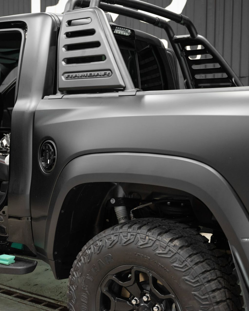 Black matte pickup truck with roll bar, rugged tires, and black fender flares.