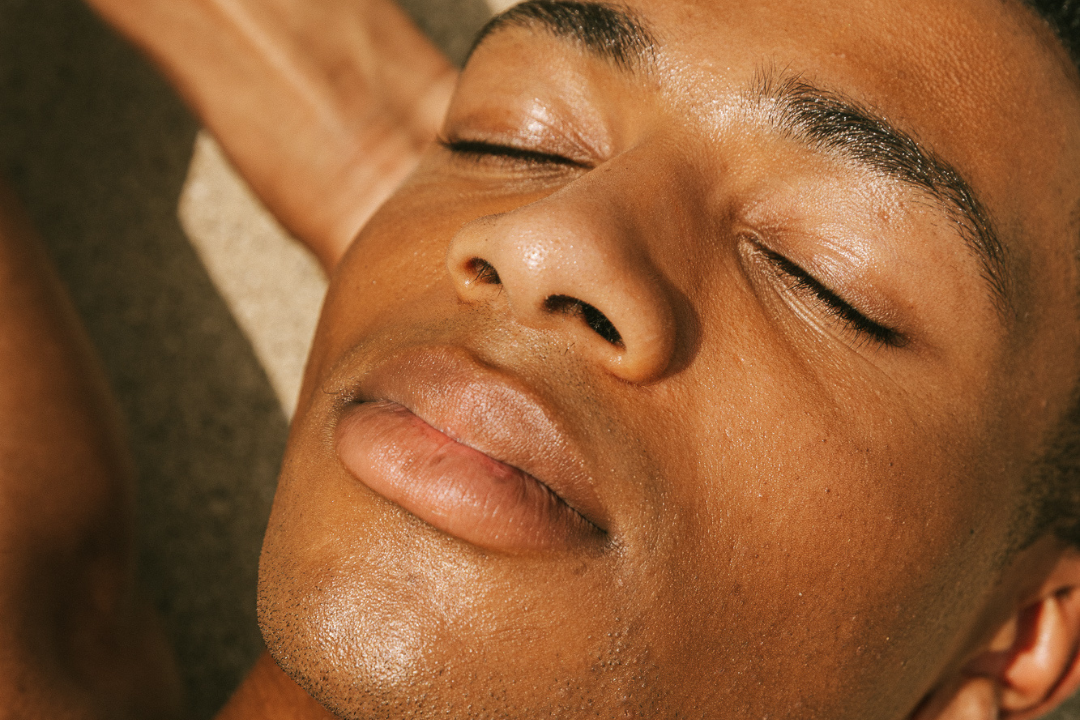 A close-up of a man's glowing face with his eyes closed.