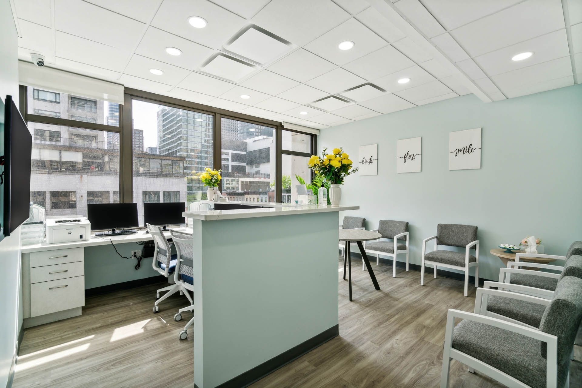 Modern office reception area with light blue walls, desk, and waiting chairs.