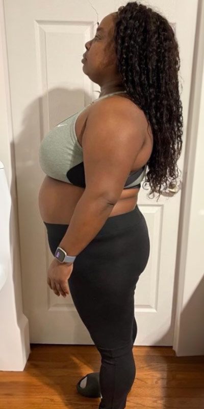 A woman in a sports bra and leggings is standing in front of a door.