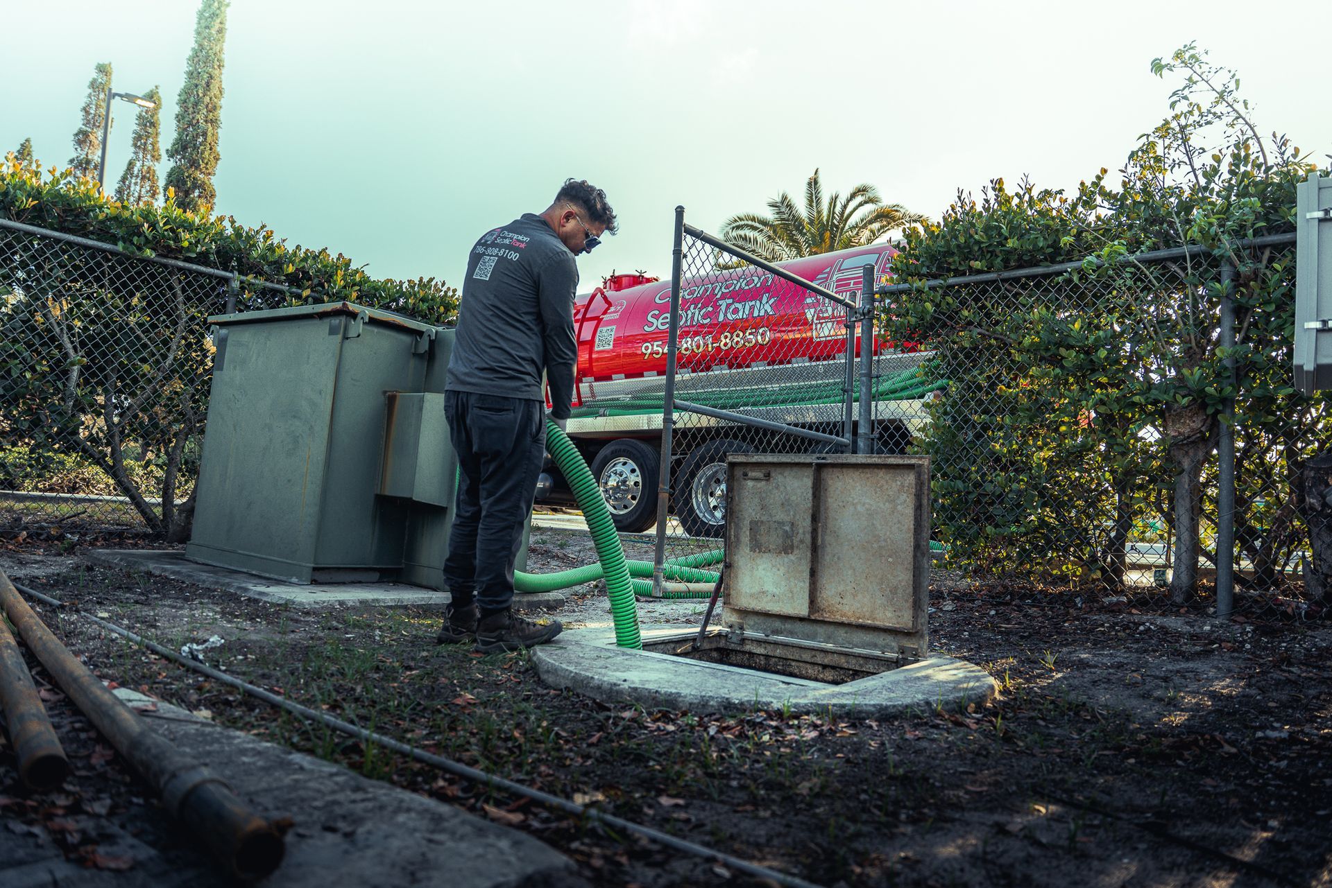 A man is pumping water from a hose into a hole in the ground.