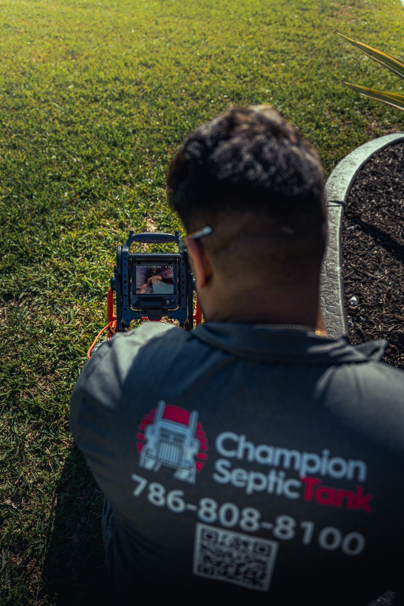 A man is standing in the grass with a camera on his back.