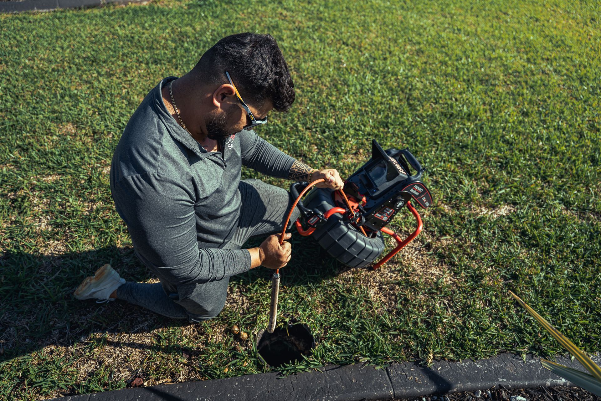 A man is kneeling down in the grass using a camera.