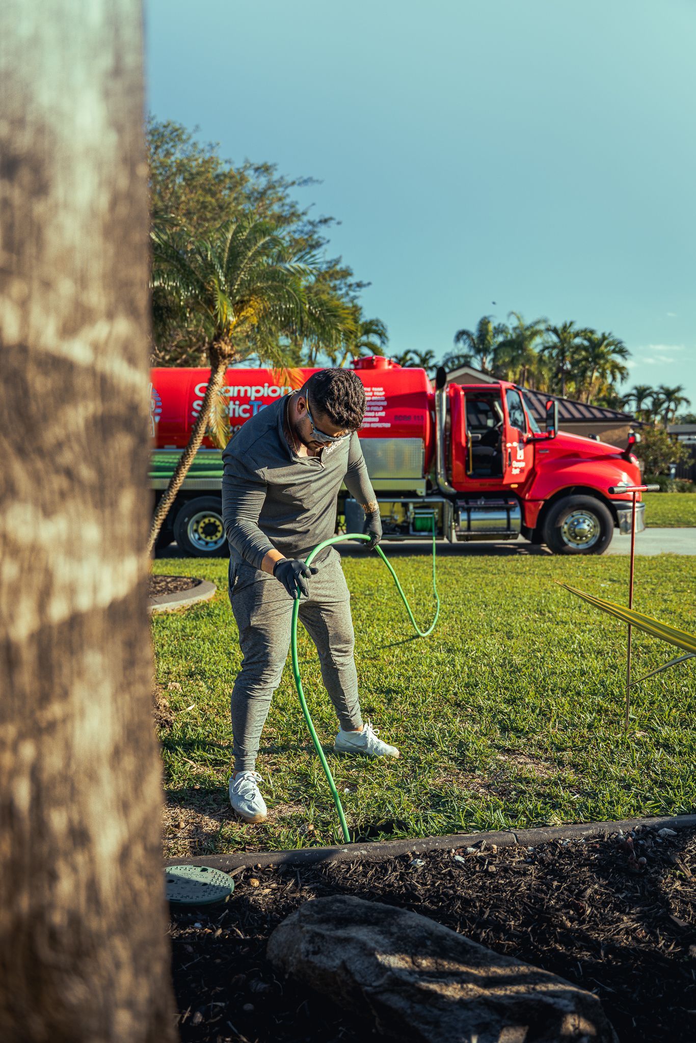 A man is holding a hose in front of a red truck.