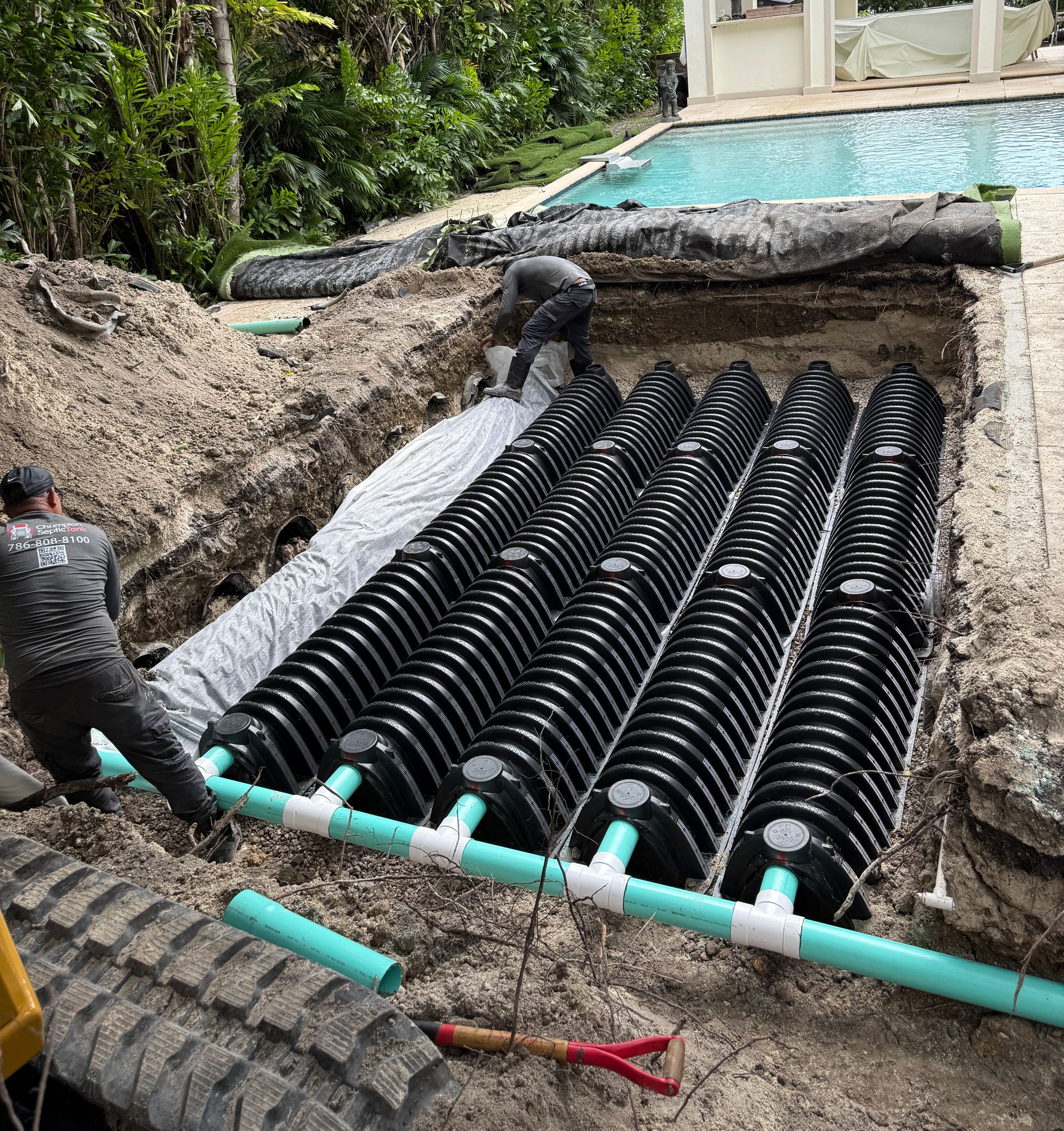A septic system is being installed in the dirt in front of a house.