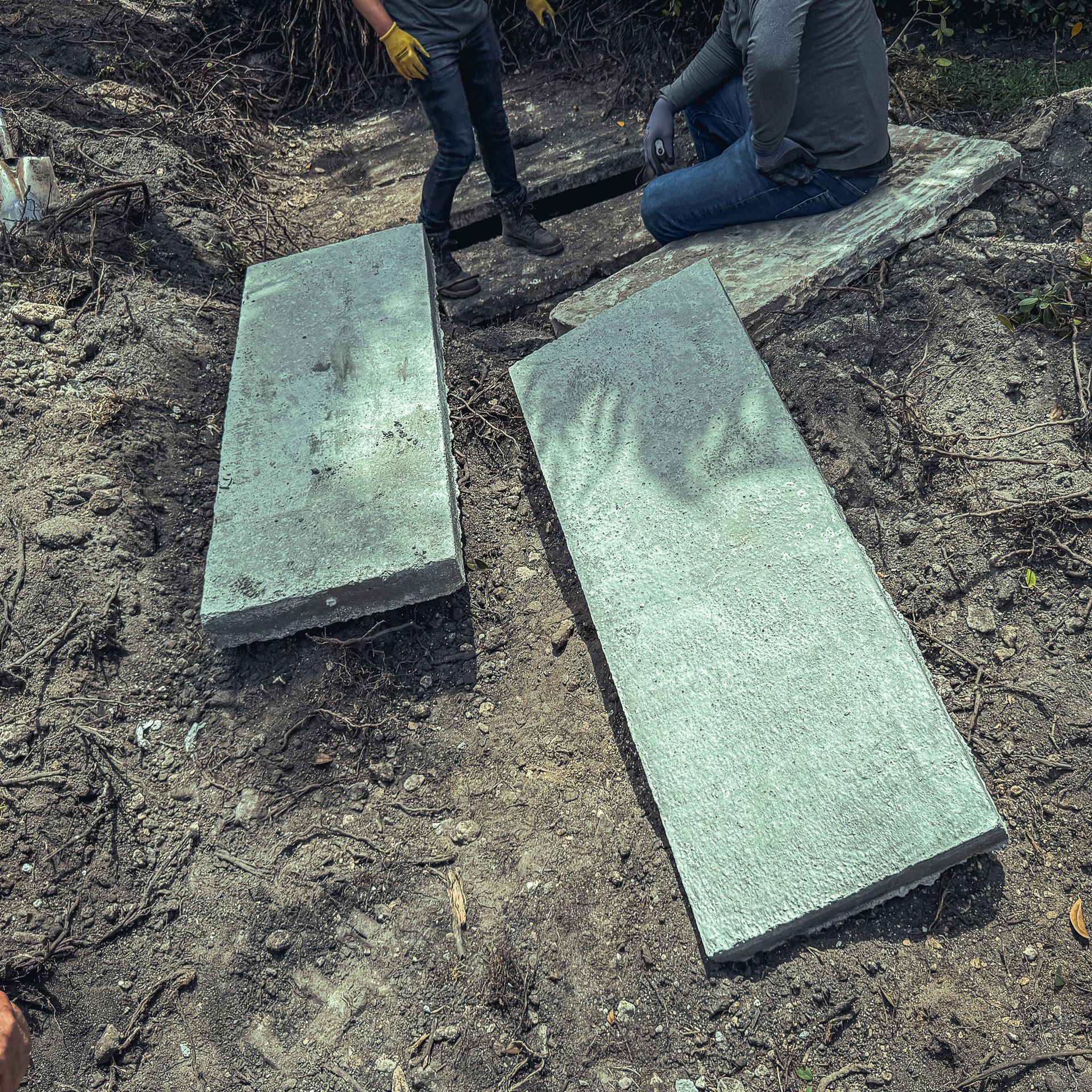 Two men are sitting on concrete slabs in the dirt