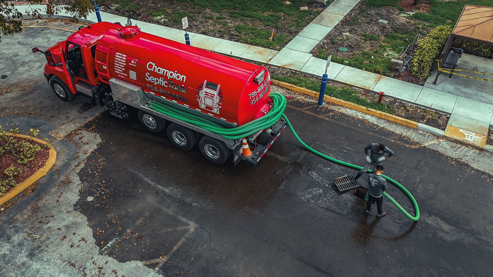 An aerial view of a red truck with a green hose attached to it.