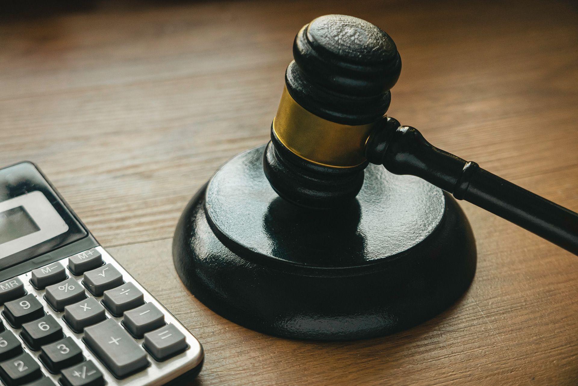 Judge’s gavel beside a calculator on a wooden desk