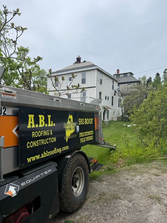 A roofing and construction truck is parked in front of a house.