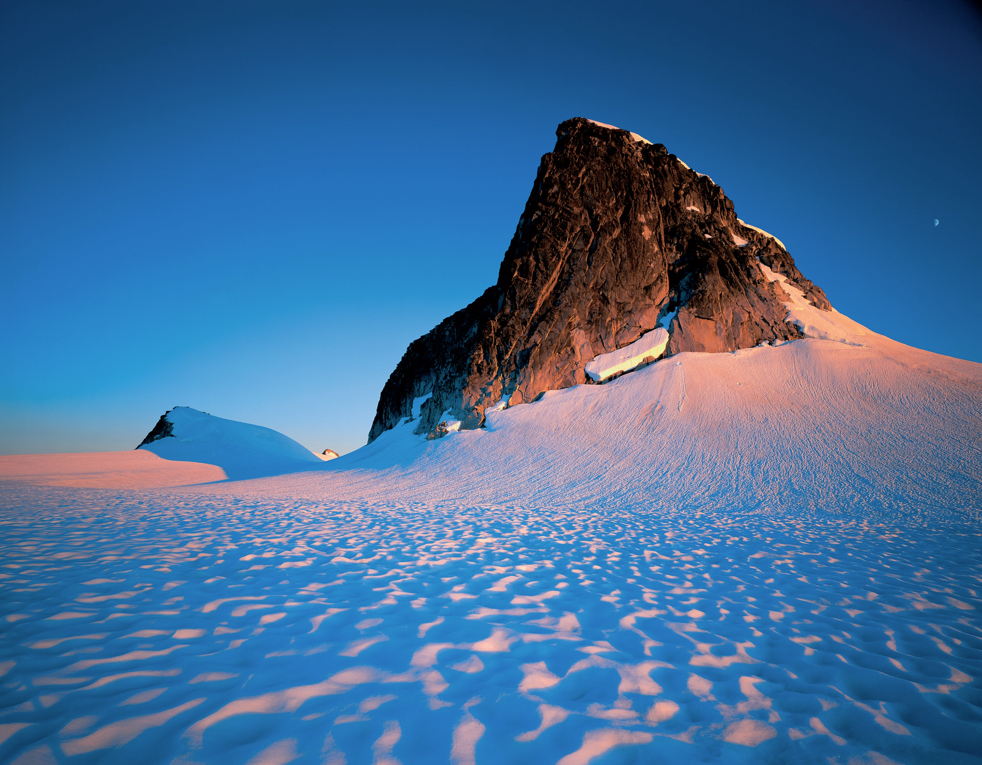 A snowy mountain with a blue sky in the background