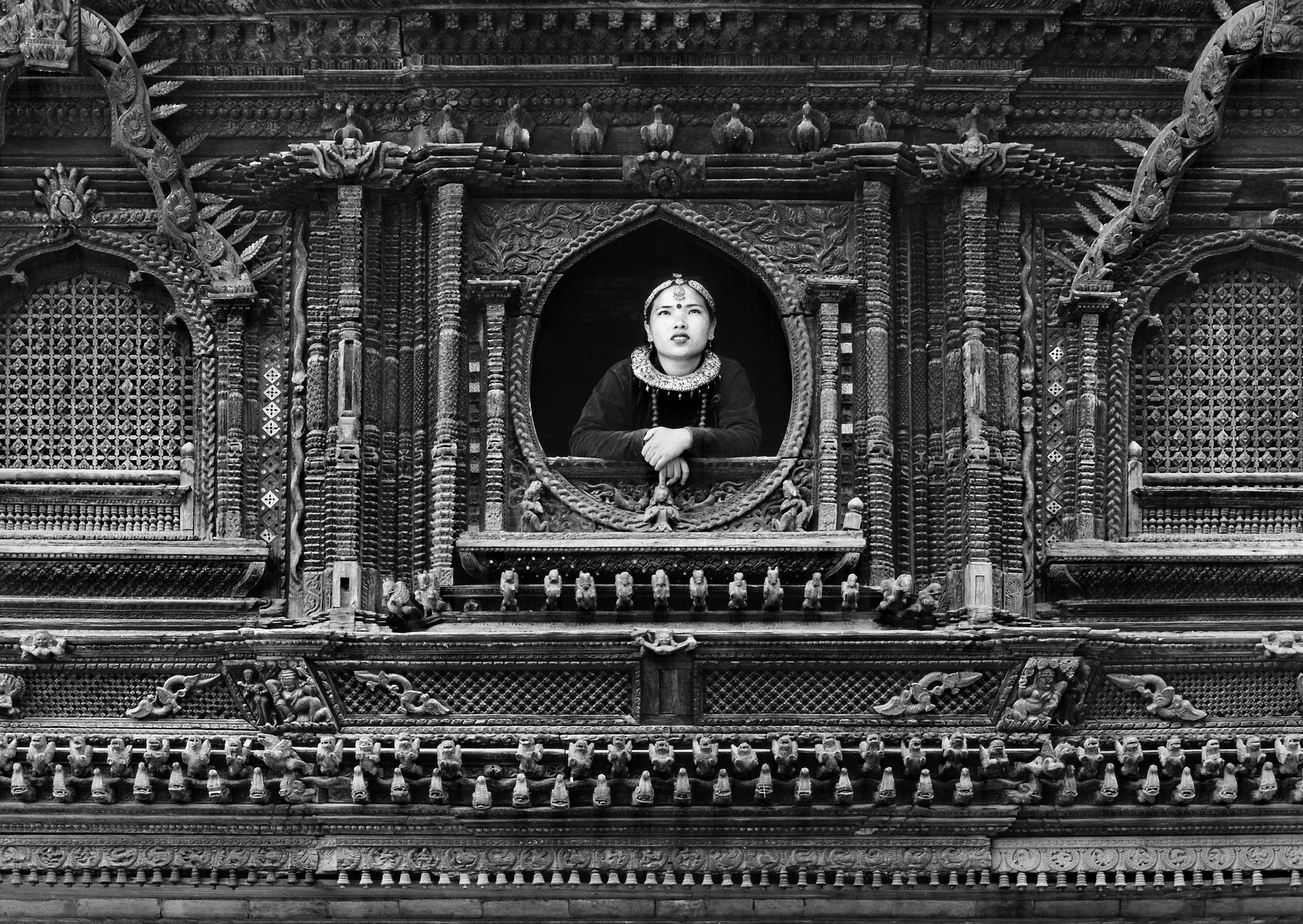 A black and white photo of a statue of a woman in a window.