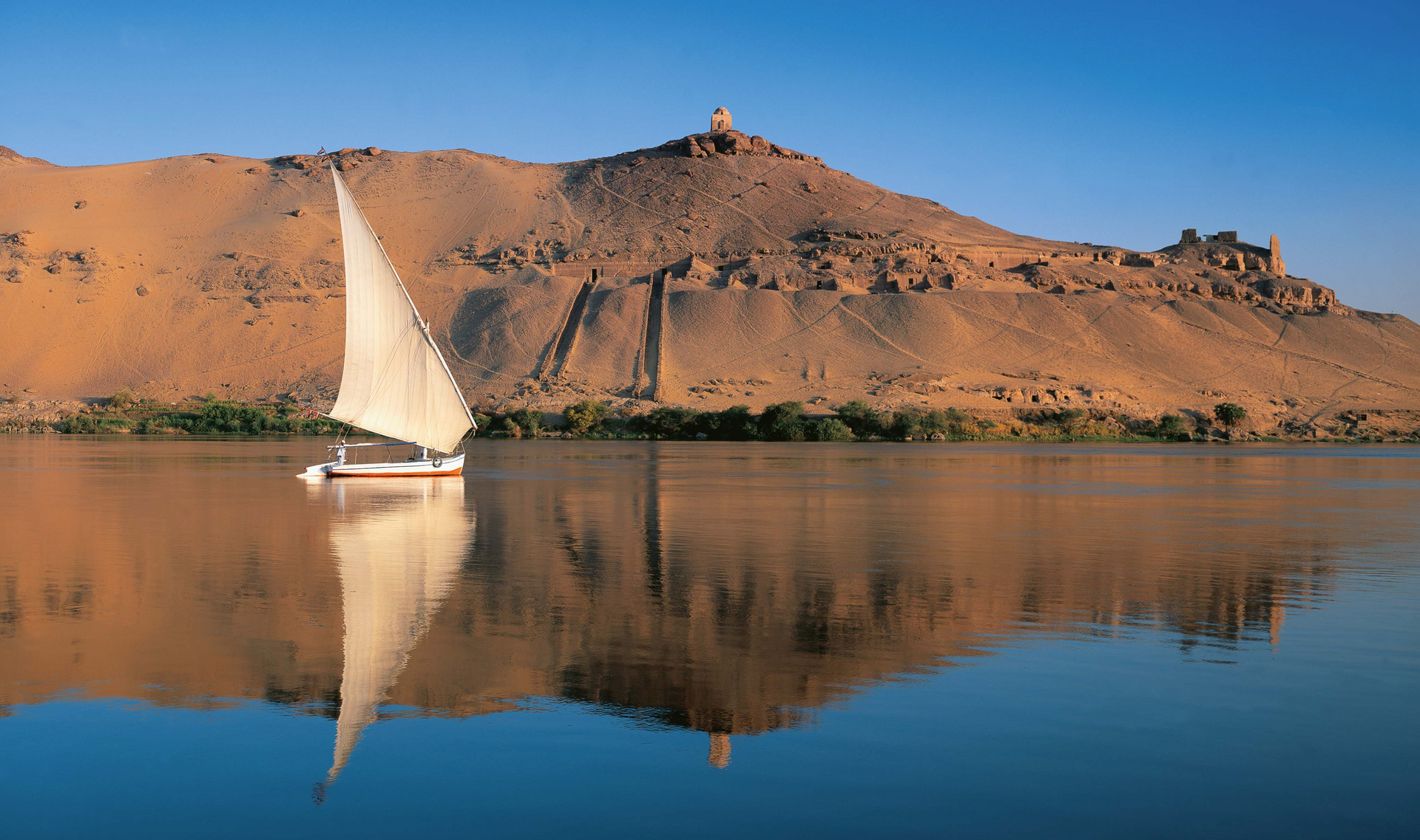A sailboat is floating on a lake with mountains in the background.