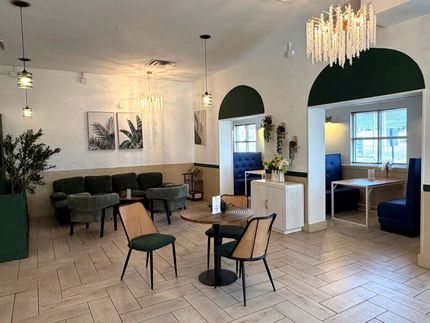 Modern lounge with green chairs, tables, sofas, and arched doorways in a bright white interior