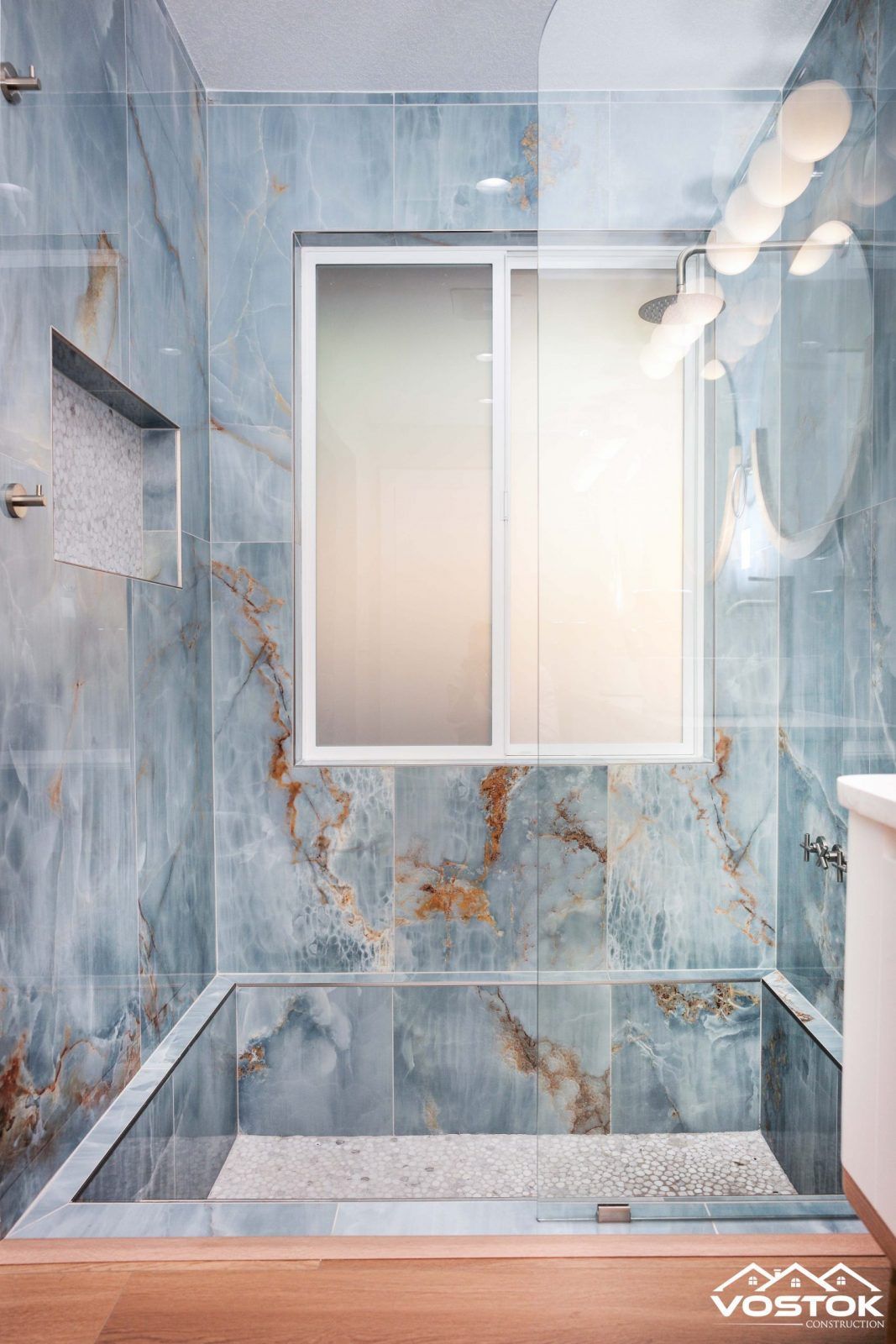 A bathroom with blue tiles and a walk in shower.