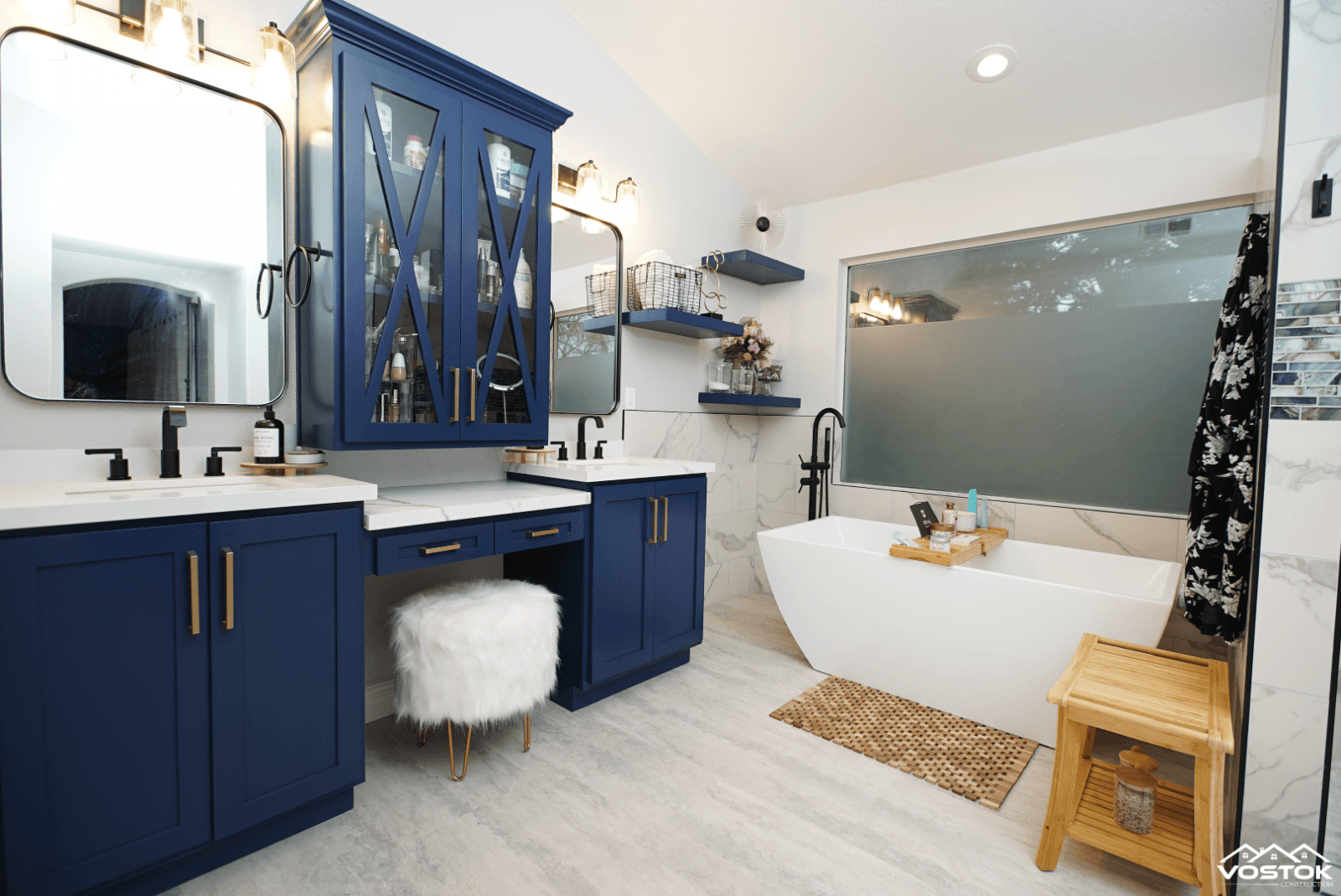 A bathroom with blue cabinets and a white tub.