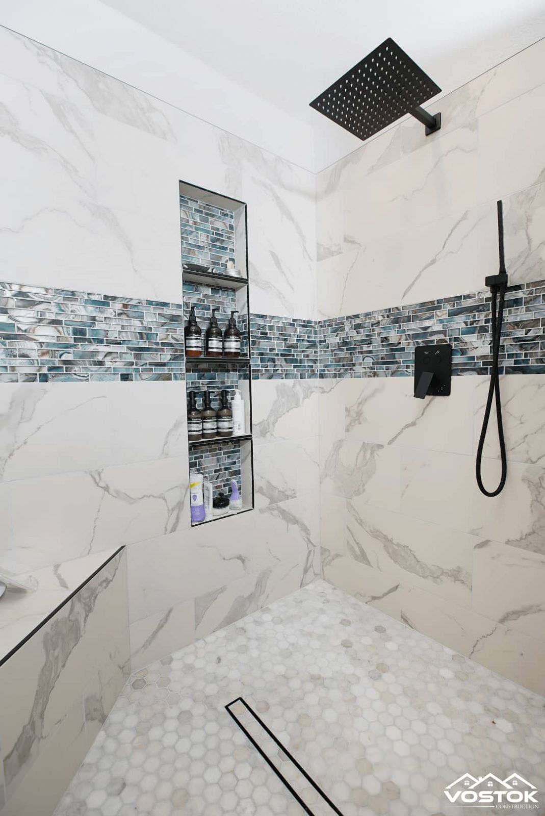 A bathroom with a walk in shower and a black shower head.