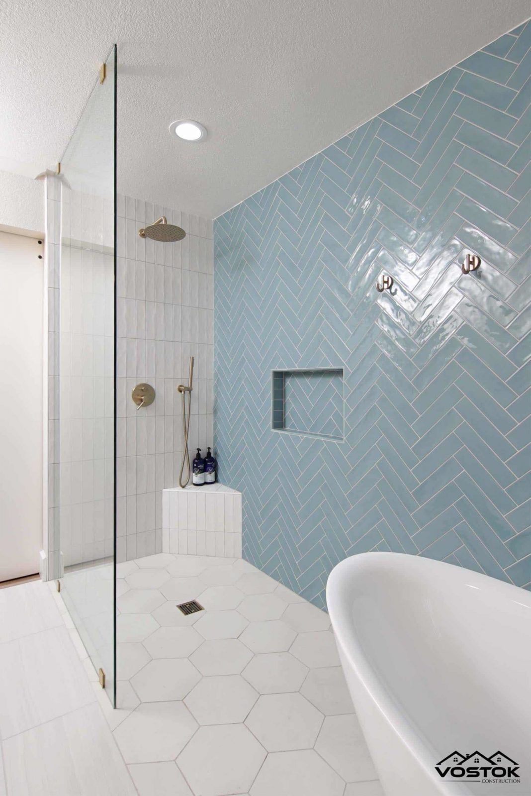 A bathroom with blue and white tiles , a walk in shower , and a bathtub.