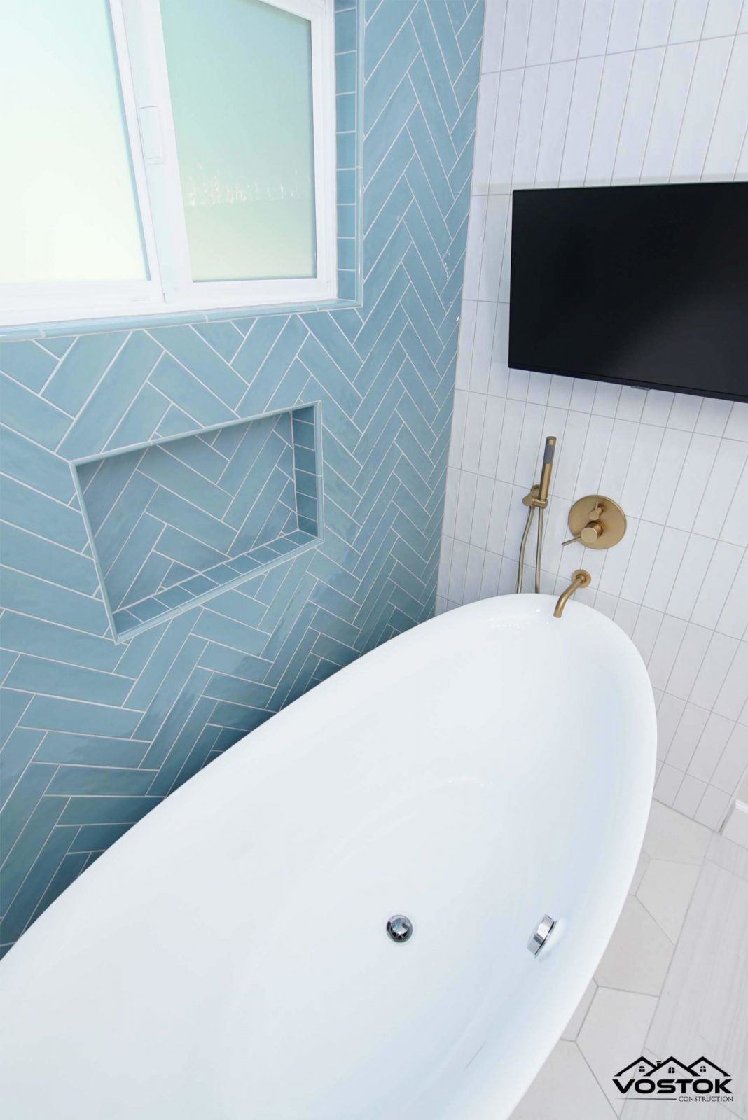 A bathroom with a bathtub and a television on the wall.