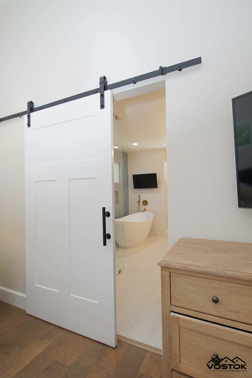 A bedroom with a sliding barn door leading to a bathroom.