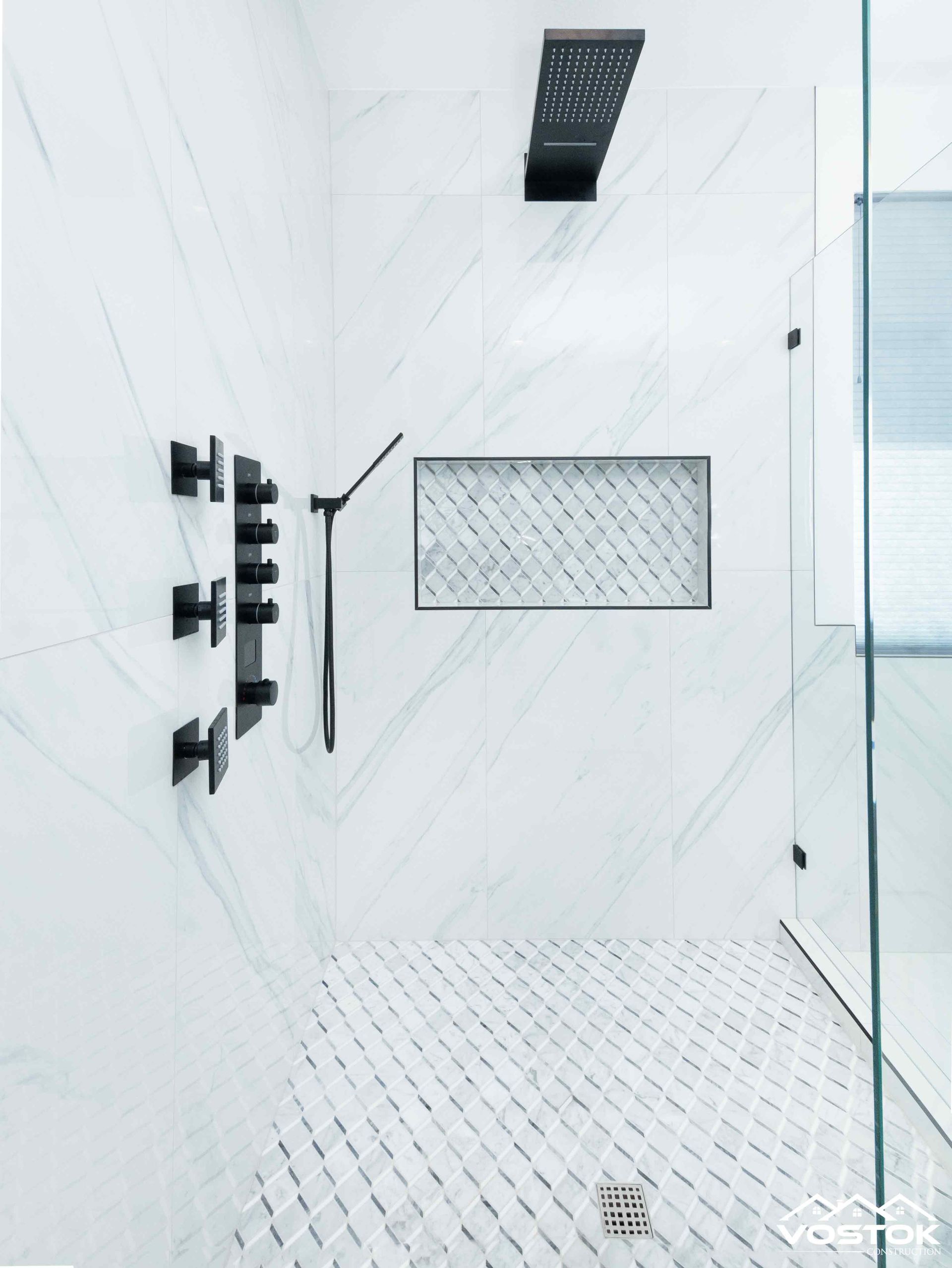 A bathroom with a walk in shower and a black shower head.