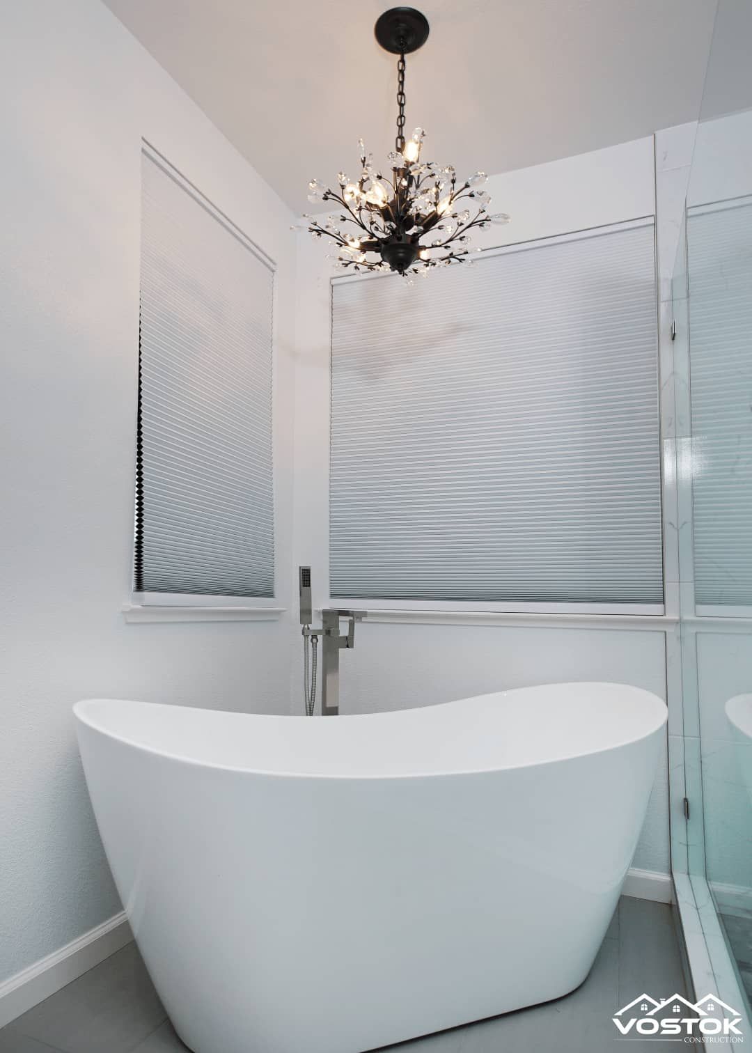 A white bathtub in a bathroom with a chandelier hanging from the ceiling