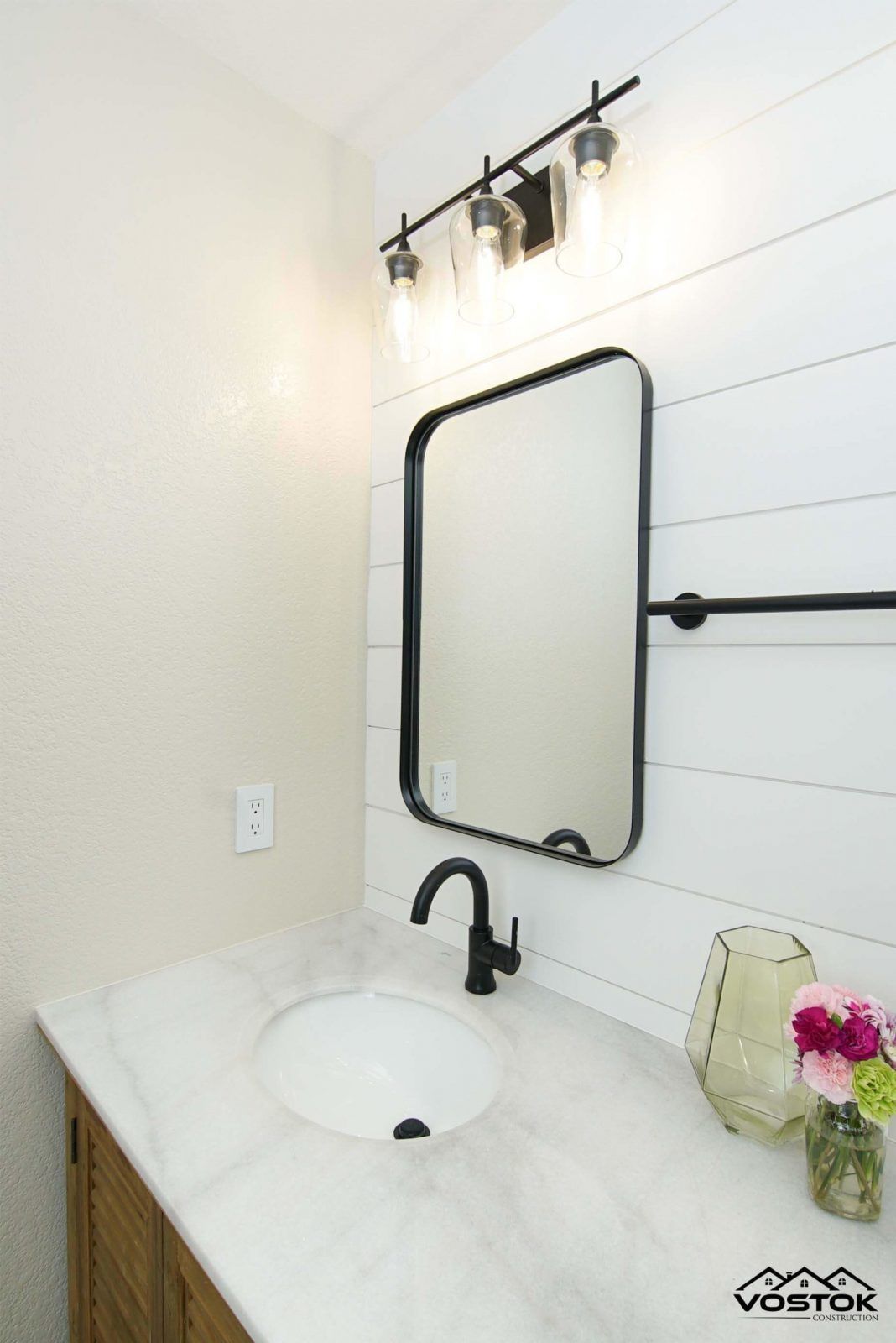 A bathroom with a sink , mirror and light fixture.