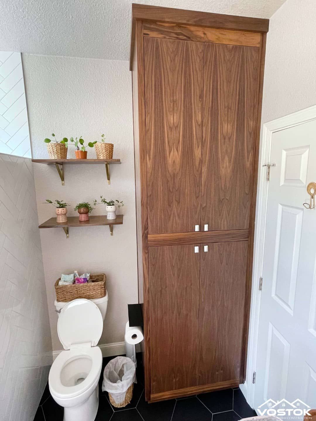 A bathroom with a toilet and a wooden cabinet.