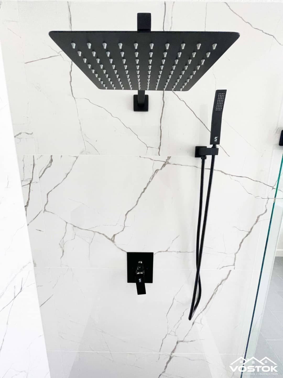 A black shower head is hanging on a white wall.