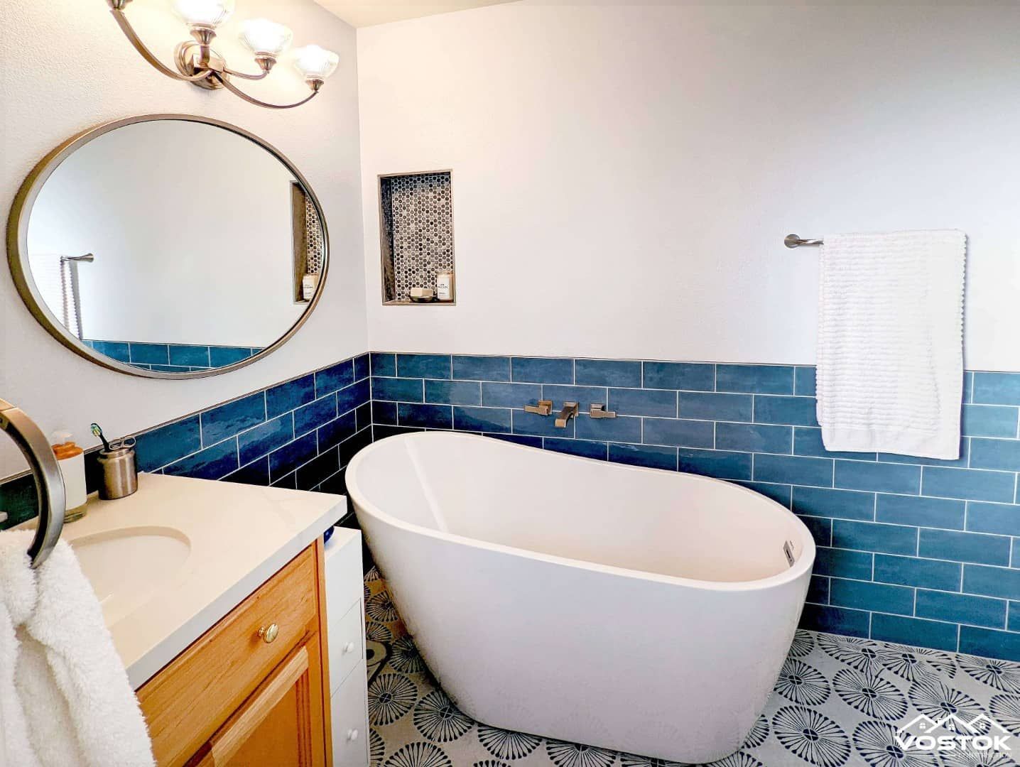 A bathroom with a bathtub , sink , mirror and blue tiles.