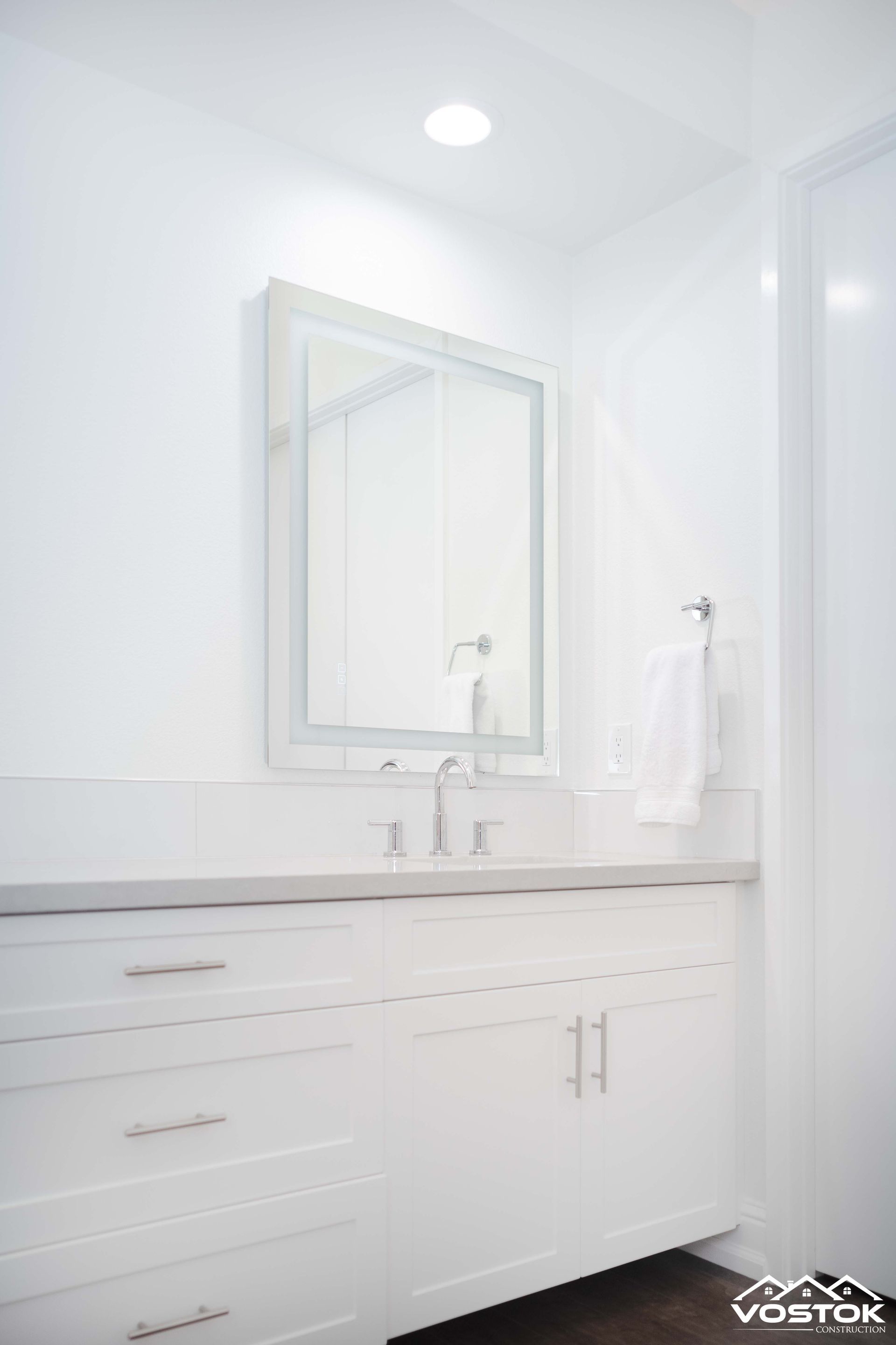 A bathroom with a sink , mirror and cabinets.