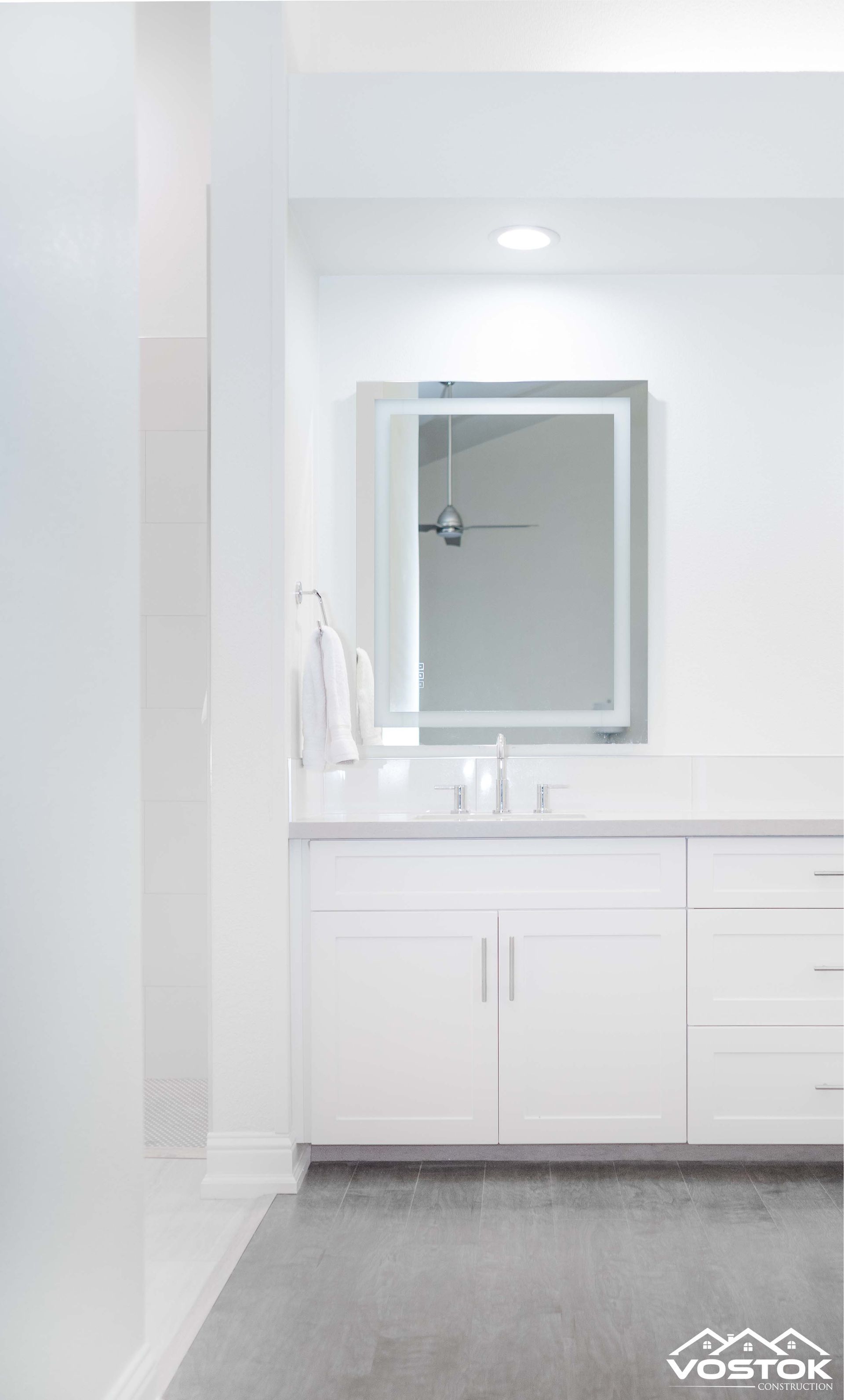 A bathroom with white cabinets , a sink , and a mirror.