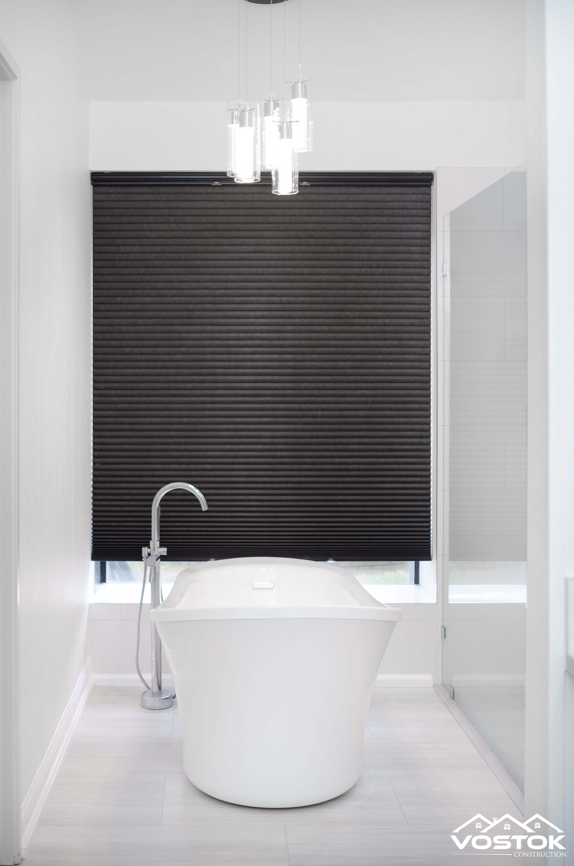 A bathroom with a bathtub and a window with blinds.