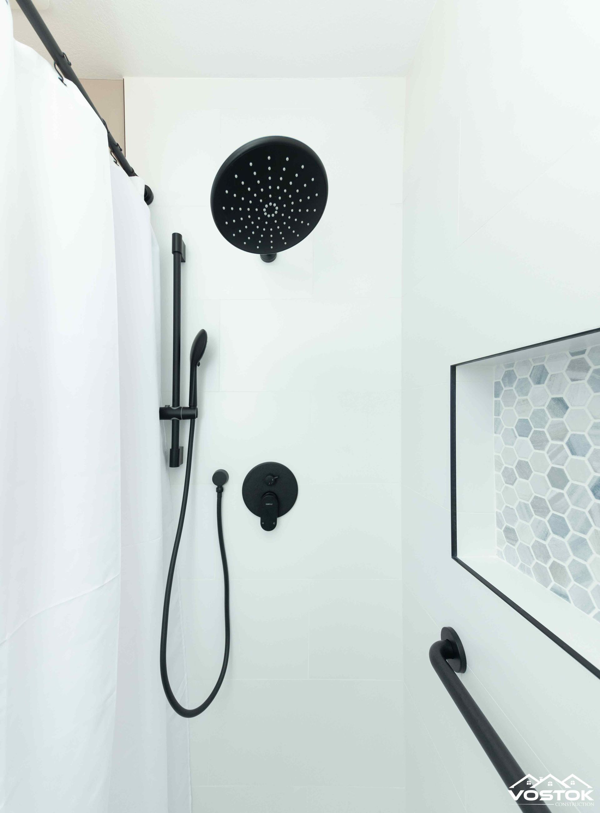 A bathroom with a black shower head and hose.