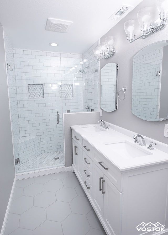 A bathroom with two sinks , a shower , and a mirror.