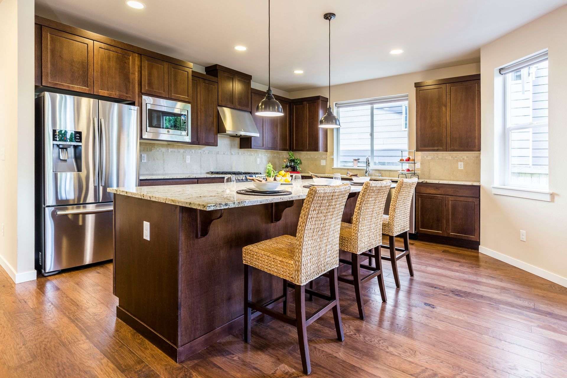 A beautiful kitchen with brown wood cabinets, wood flooring, and tan seating and accent wall