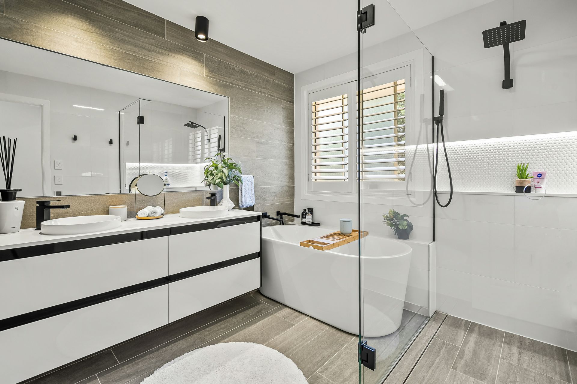 A beautiful bathroom with white counters, frameless shower, and a bathtub