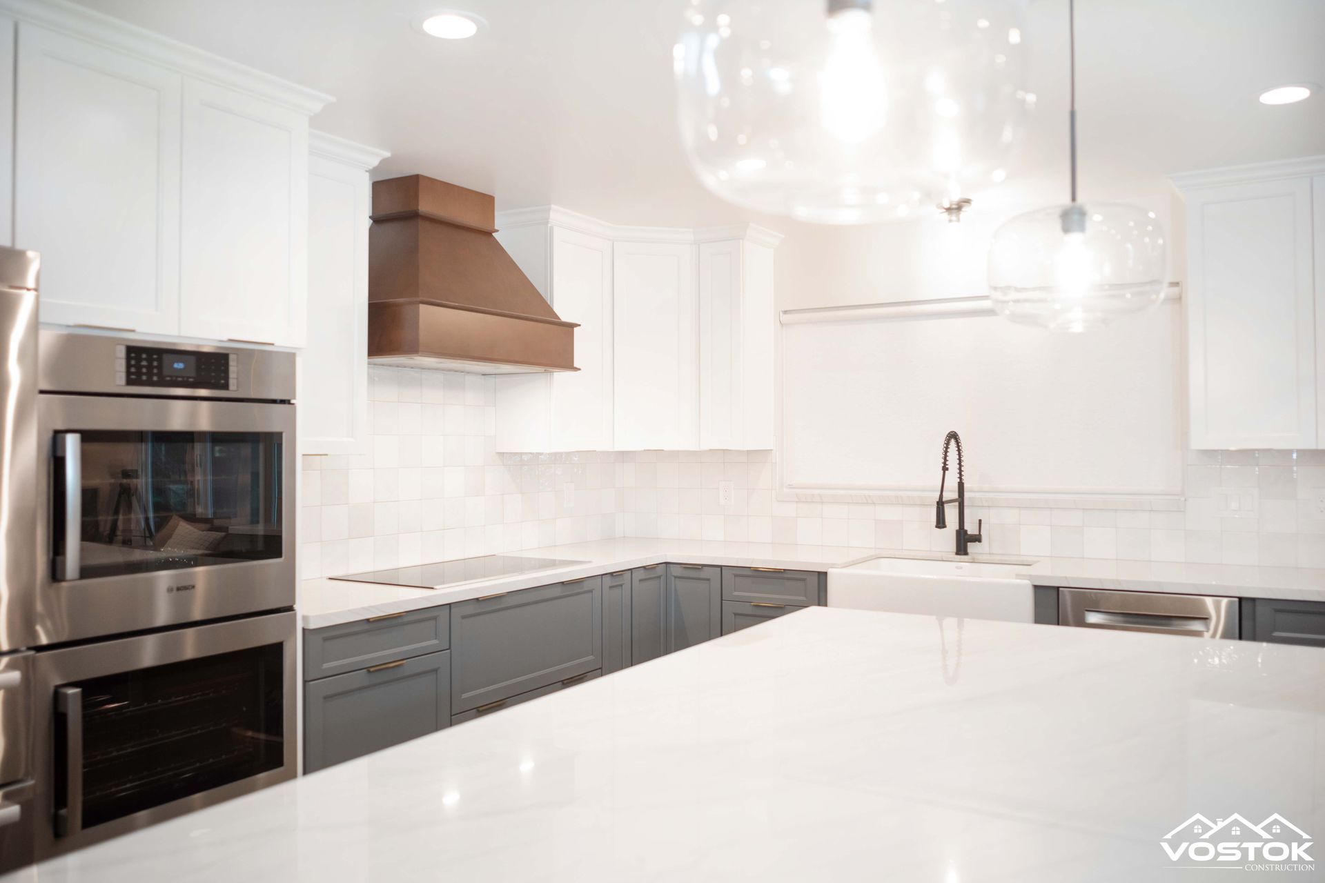 A kitchen with white cabinets , stainless steel appliances , and a large island.