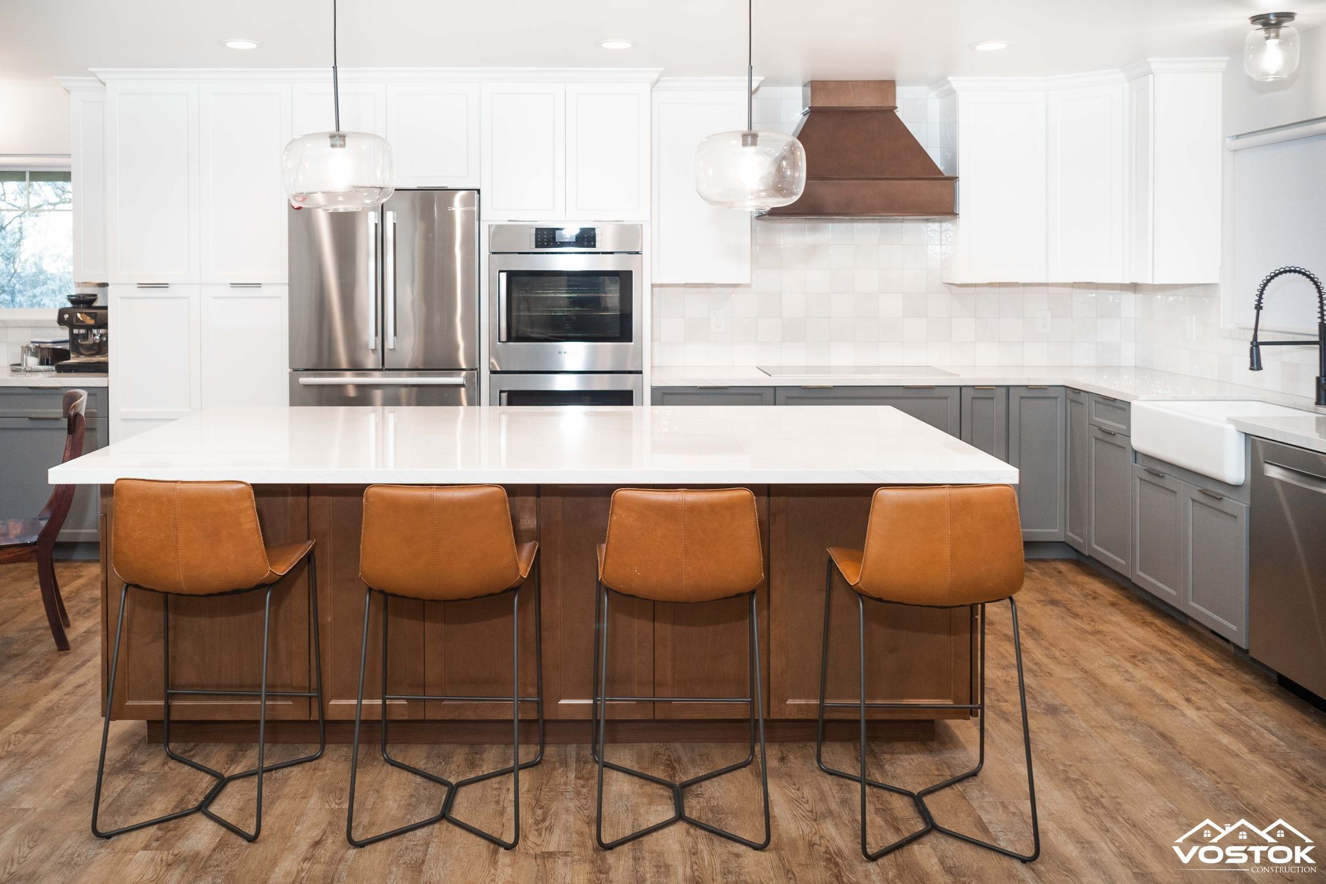 A kitchen with white cabinets , stainless steel appliances , and a large island.