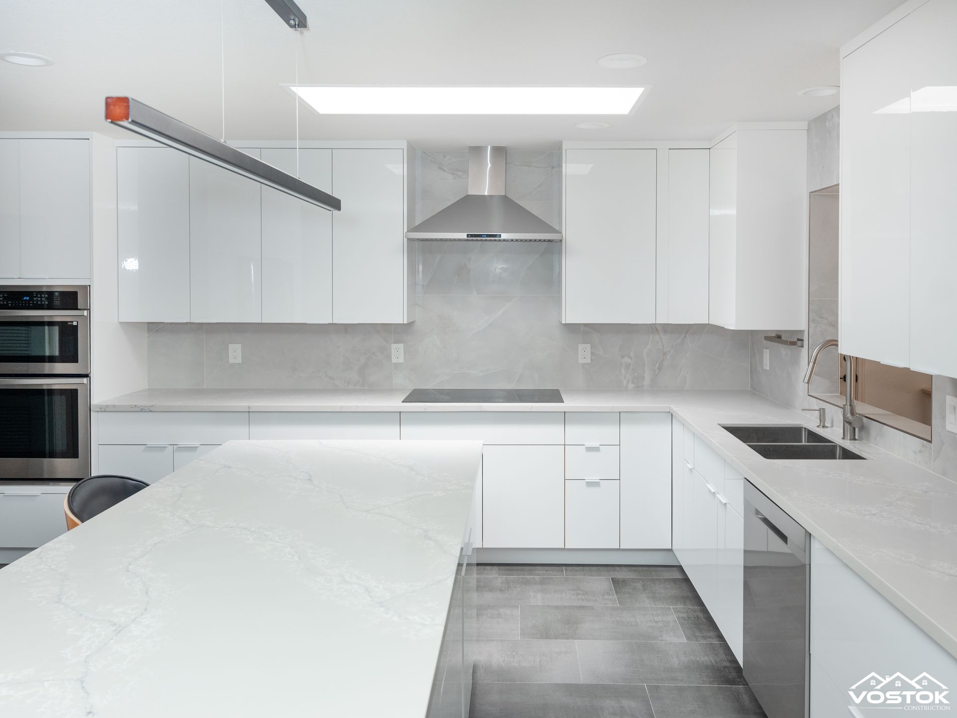 A kitchen with white cabinets , stainless steel appliances , and a large island.